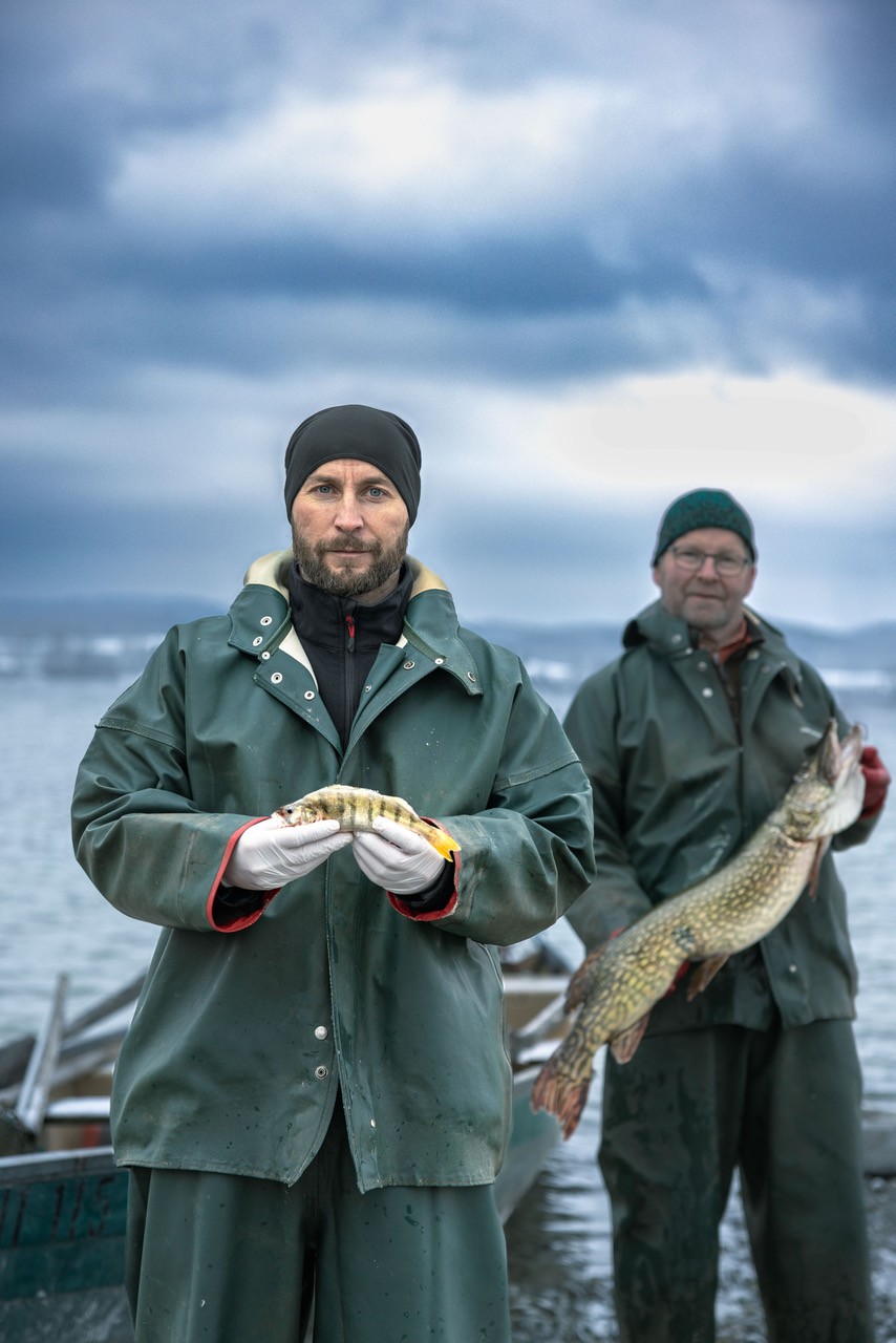 älterer Fischer mit großem Fisch jüngerer Fischer mit kleinem Fisch